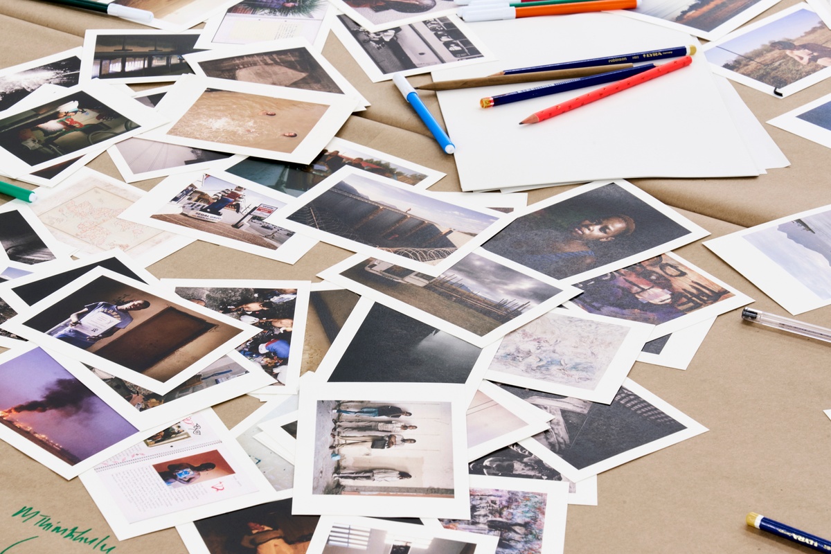 Event photograph from the roundtable discussion that accompanied the ‘Tell It to the Mountains’ exhibition in A4’s gallery. A close-up view of a table covered in brown paper and strewn with postcard size printouts of Lindokuhle Sobekwa and Mikhael Subotzky’s photographs.
