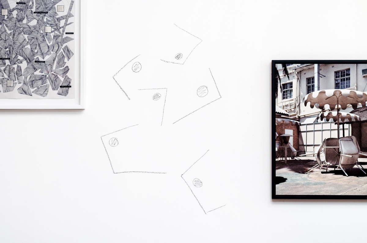 Installation photograph from the ‘Between Two or More Worlds’ exhibition at the 2016/2017 A4 Office. In the middle, a charcoal drawing made directly on the wall. On the right, Thabiso Sekgala’s photograph ‘The Terrace Hotel, Hulawayo’ is mounted on the wall.
