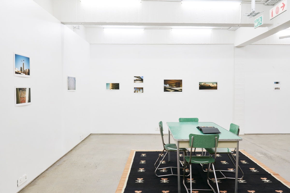 Installation photograph from the ‘Missing Subject’ exhibition in A4’s Library. On the right, a laminate table features a photo album with Andile Phewa’s photographs. On the left and back, Phewa’s photographs line the walls.
