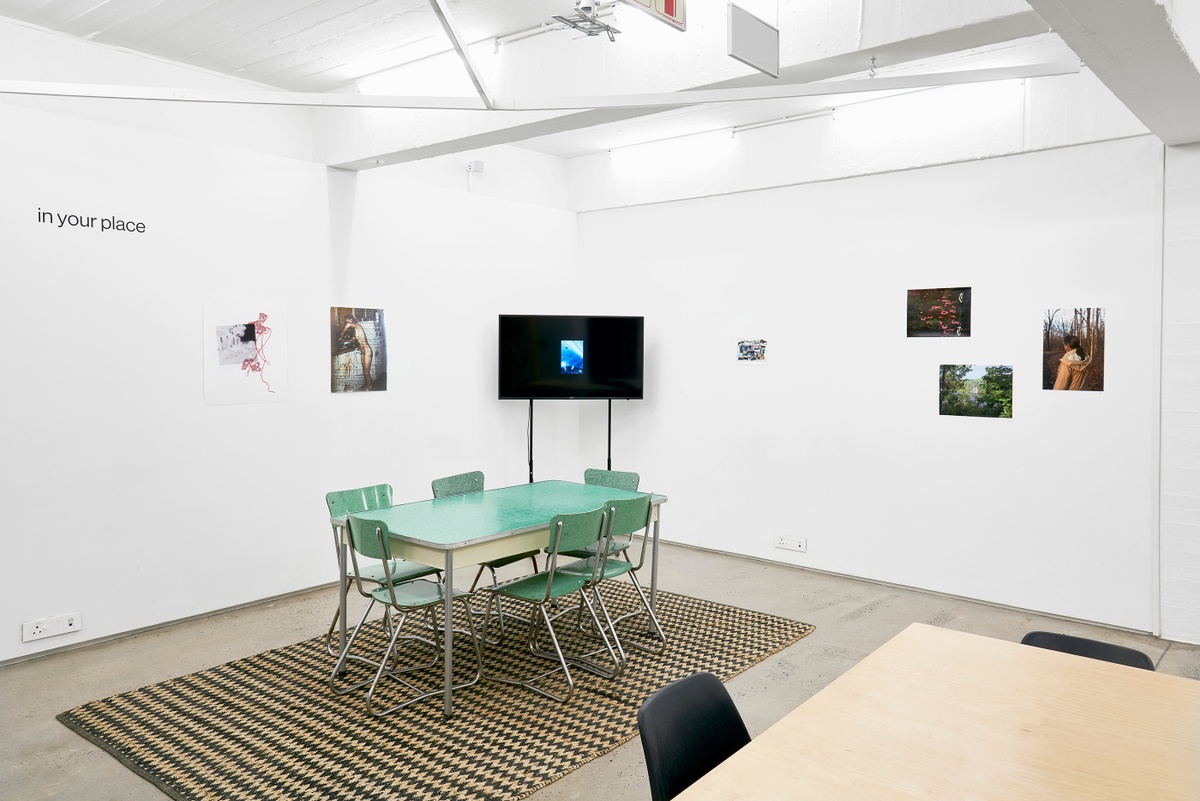 Installation photograph from the ‘In Your Place’ exhibition on A4’s ground floor. On the left, Pippa Hetherington’s collage ‘The Rest Is Memory #1’ and Lily Mott’s print ‘Housewife’ are mounted on the wall. In the middle, Eugene Lee’s video ‘Untitled (not so keyword)’ is displayed on a freestanding screen. On the right, Tomo Morisawa’s untitled photo-collage, Andrea Martucci’s photograph “from Of this Being,” Genevieve Fournier’s photograph “Untitled (Mom)” and Ali Di Lucia’s photograph ‘Cliff jump’ are mounted on the wall.
