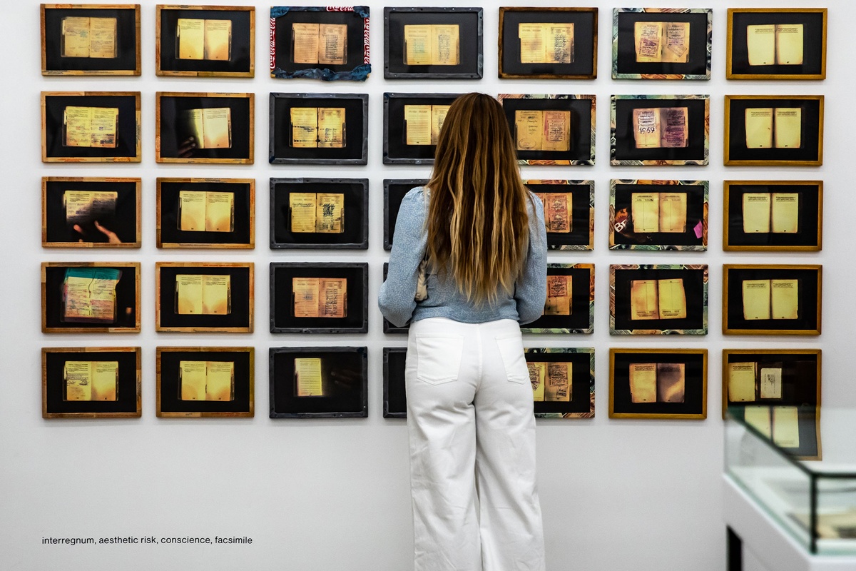 Event photograph from the opening of the Photo Book! Photo-Book! Photobook! exhibition in A4’s Gallery in an area used to house photobooks from the years 1967 to 1994. An attendee stands in front of Sue Williamson’s photographic series ‘For Thirty Years Next to His Heart’.
