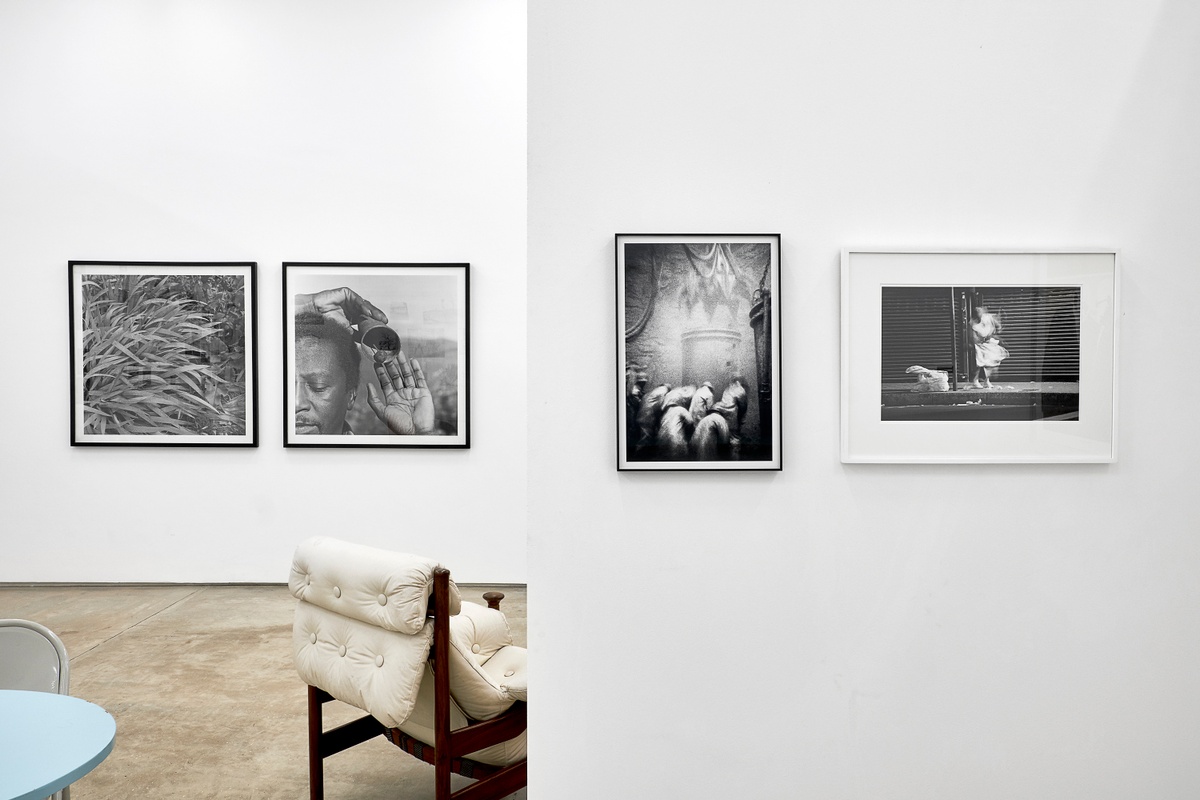 Installation photograph from the 2018 rendition of ‘Parallel Play’ in A4’s Gallery. At the back, George Hallet’s monochrome photographic diptych ‘Peter Clarke’s Tongue’ is mounted on the gallery wall. At the front, David Goldblatt’s monochrome photograph ‘Shaftsinking: the cactus grab has dumped the last load of big rocks into the kibble, now the men clear the smaller rocks from the bottom, loading the kibble with shovels. President Steyn No. 4 Shaft, Welkom, Orange Free State, June 1969 – 3\_E7083’ and Sabelo Mlangeni’s monochrome photograph ‘Invisible Woman I’ is mounted on the wall.
