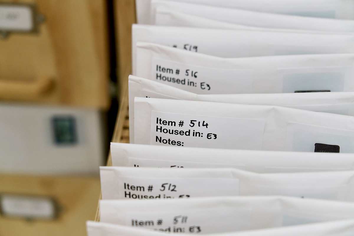 Installation photograph from the 'A Little After This' exhibition in A4 Arts Foundation's gallery that shows collected objects from Penny Siopis' 'Will' work organised in envelopes, which in turn are arranged in bespoke wooden filing cabinets.
