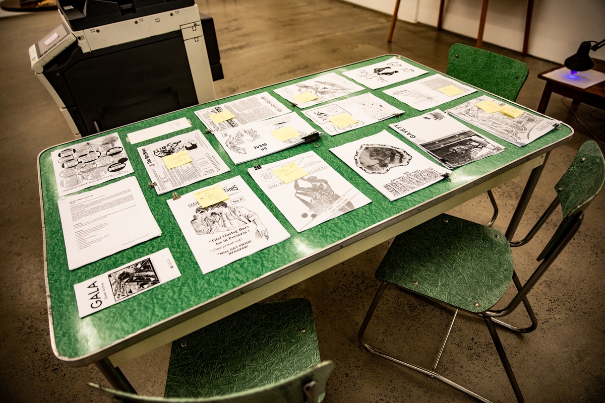 Event photograph from the opening of the Papertrails exhibition in A4’s Reading Room shows bundles of photocopied reading material arranged on a green laminate table.
