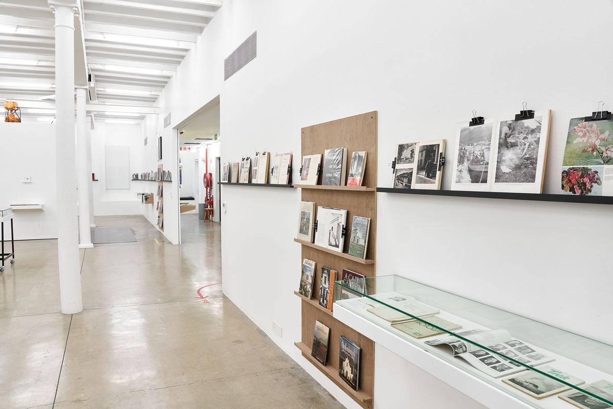 Installation photograph from the Photo Book! Photo-Book! Photobook! exhibition in A4’s Gallery. On the right, shelving units with printed matter from the years 1945 to 1967 line a white gallery wall.
