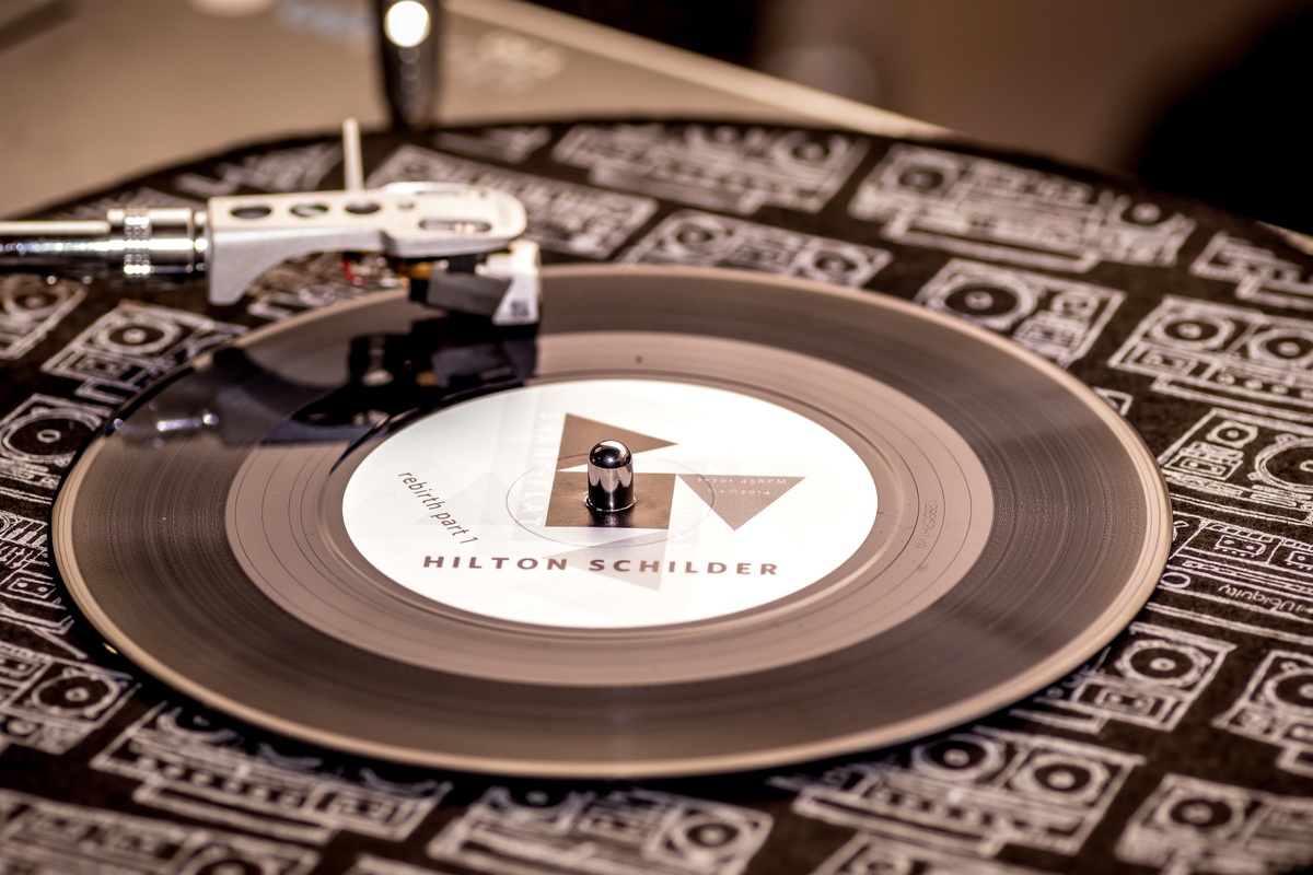 Event photograph from a performance by Shabaka and the Ancestors, with special guest Bra Louis Moholo-Moholo, on A4’s top floor that depicts Hilton Schilder’s vinyl ‘rebirth part 1’ mounted on a record player.
