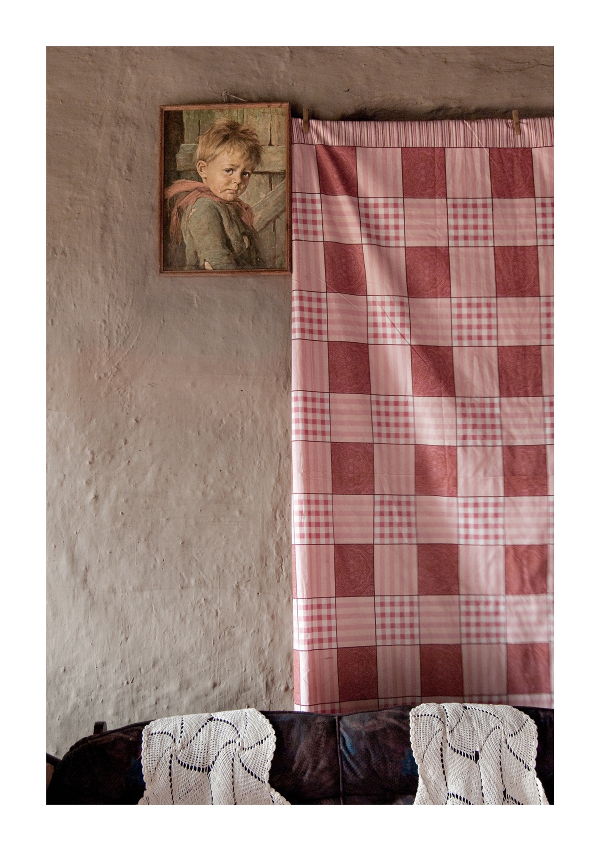 Photograph from Jabulani Dhlamini’s residency on A4’s top floor. On the left, a reproduction of a painting of a child is mounted on the wall. On the right, a curtain covers a window.
