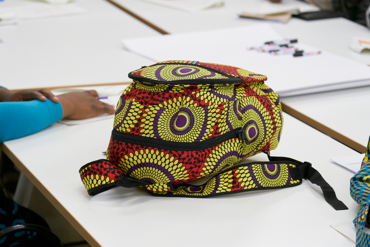 Event photograph from the Scalabrini Workshop that formed part of ‘Open Production’, Igshaan Adams’ hybrid studio/exhibition in A4’s Gallery. In the middle, a backpack sits on a table.
