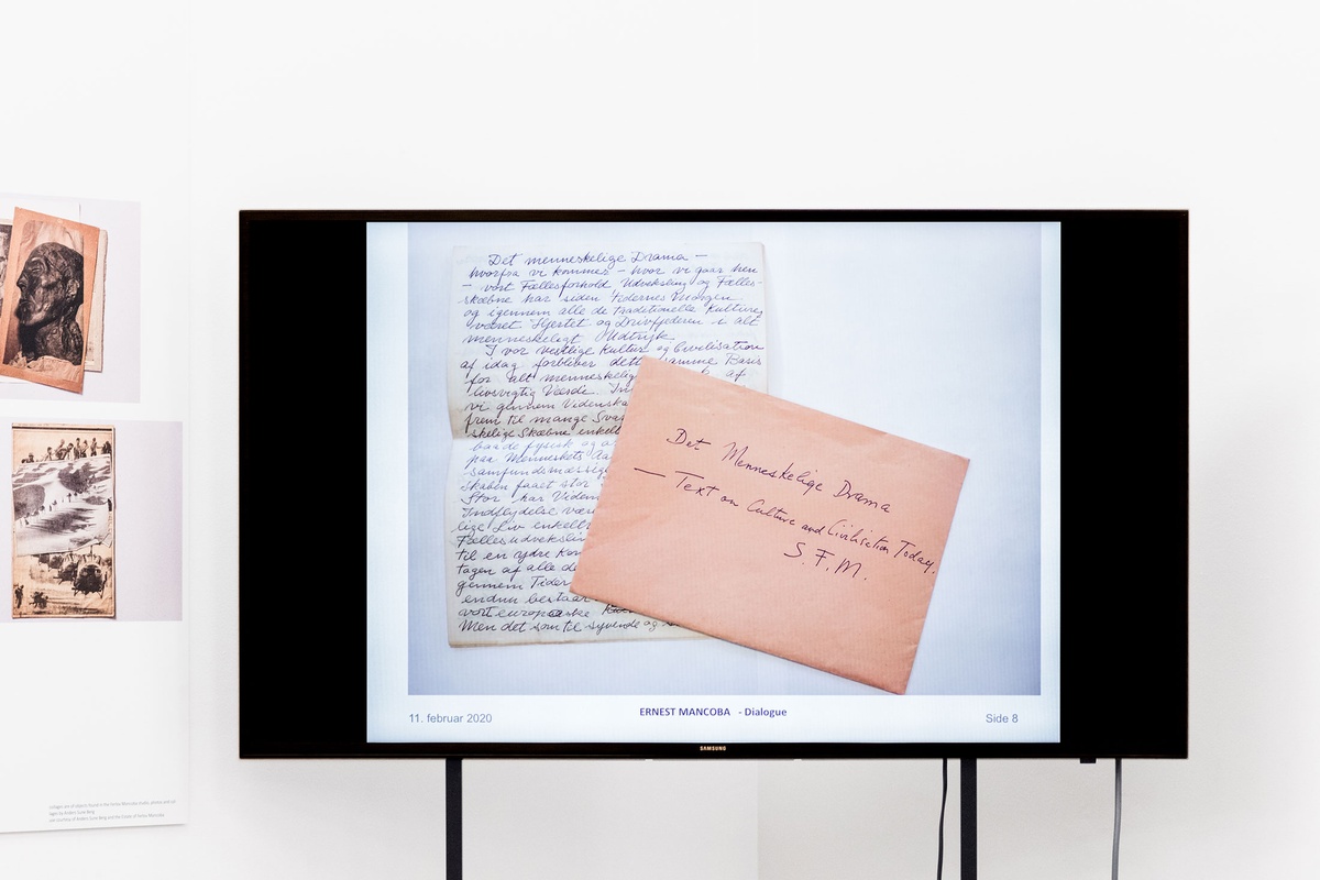 Event photograph from the Ernest Mancoba Symposium at A4 Arts Foundation. A freestanding screen displays a photograph of a handwritten letter and envelope with caption reading 'Ernest Mancoba - Dialogue'.
