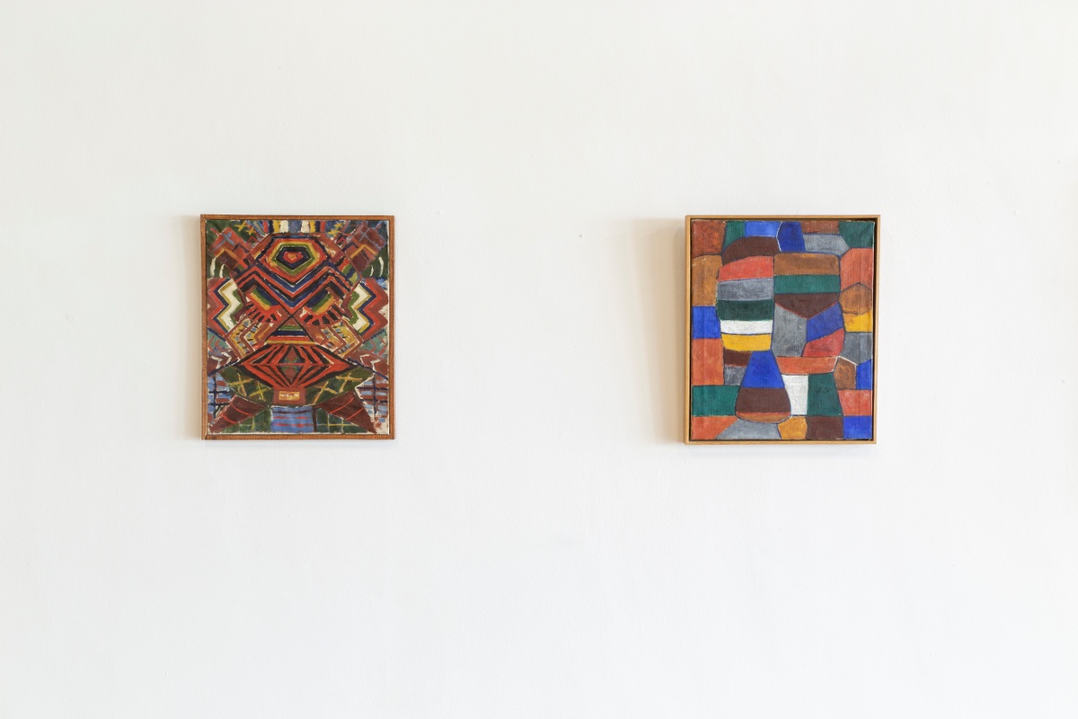 Installation photograph from the ‘Ernest Mancoba Symposium: A dialogue on his art and words’ on A4’s ground floor. On the left, Ernest Mancoba’s oil painting ‘Komposition’ is mounted on a white wall. On the right, an untitled oil painting by Mancoba is mounted on the wall.
