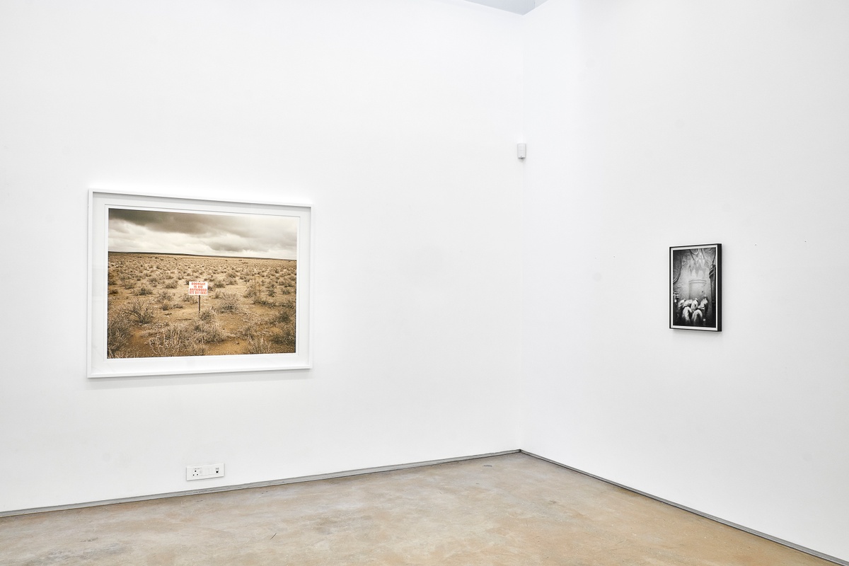 Installation photograph from the ‘Picture Theory’ exhibition in A4’s Gallery. On the left, David Goldblatt’s photograph ‘Boorgat is die Antwoord, De Brak, on the Fraserburg-Sutherland road. Western Cape’ is mounted on the gallery wall. On the right, Goldblatt’s monochrome photograph ‘The last of the bigger rocks has just been dropped into a kibble. Now with shovels, the team 'lashes' (load) the small stuff into the kibble’ is mounted on the gallery wall.
