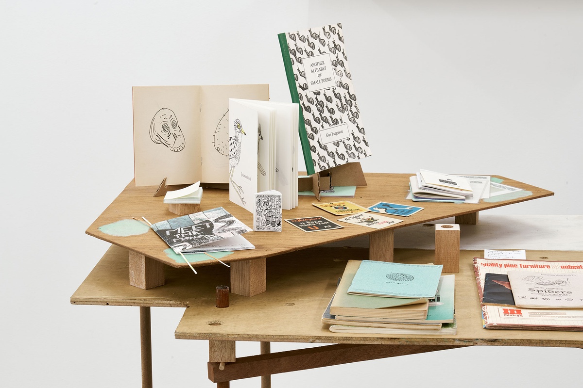 Installation photograph from the Papertrails exhibition in A4’s Reading Room. Various forms of printed matter are arranged on a custom wooden display table.
