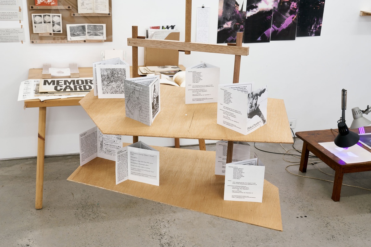 Installation photograph from the Papertrails exhibition in A4’s Reading Room. Custom wooden shelves are suspended from the ceiling, hosting printed flyers from John Peffer and Bettina Malcomess’ Think of Number 6 exhibition.
