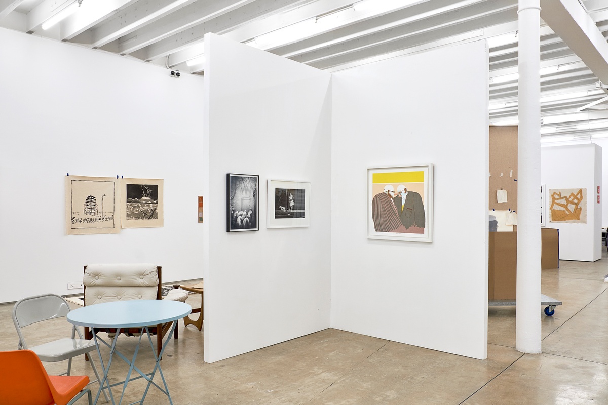 Installation photograph from the 2018 rendition of ‘Parallel Play’ in A4’s Gallery. In the middle, David Goldblatt’s monochrome photograph ‘Shaftsinking: the cactus grab has dumped the last load of big rocks into the kibble, now the men clear the smaller rocks from the bottom, loading the kibble with shovels. President Steyn No. 4 Shaft, Welkom, Orange Free State, June 1969 – 3\_E7083’, Sabelo Mlangeni’s monochrome photograph ‘Invisible Woman I’ and  Robert Hodgins’ colour screenprint ‘Twin Cigars’ are mounted on a moveable gallery wall.
