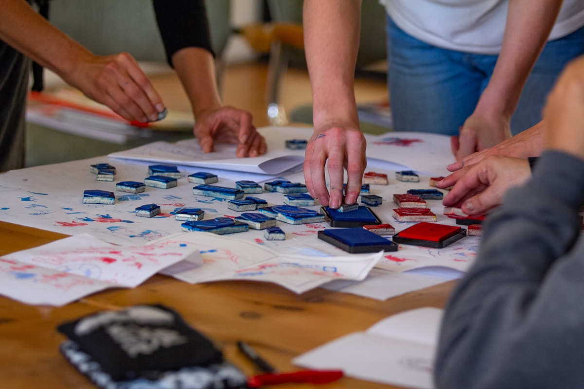 Event photograph from the 2018 rendition of the Open Book festival on A4’s ground floor that shows attendees using letter stamps and ink on paper.
