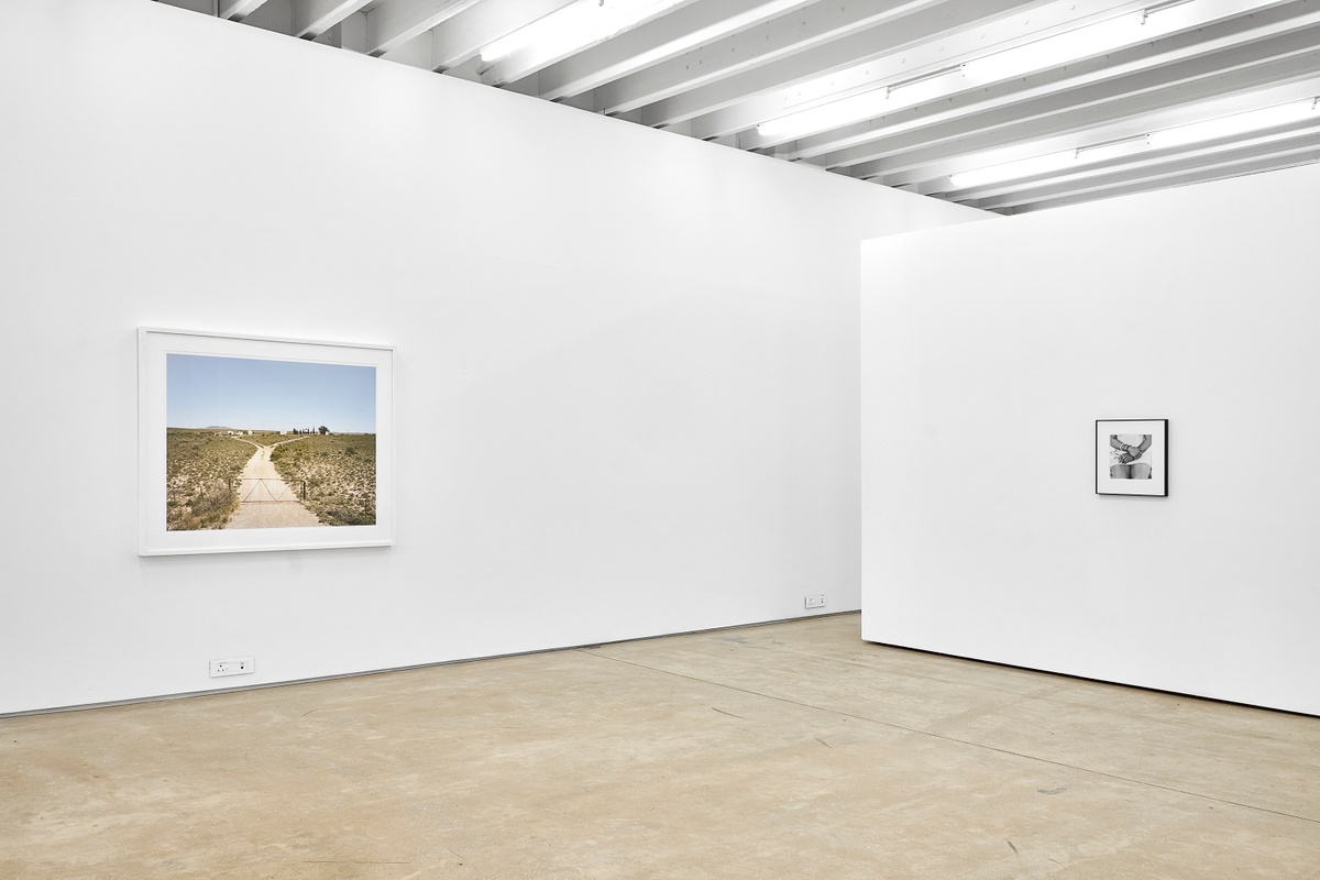 Installation photograph from the ‘Picture Theory’ exhibition in A4’s Gallery. On the left, David Goldblatt’s photograph ‘Deserted farm. Holgatsfontein in the Leeukopspan area, between Britstown and Vosburg, Northern Cape’ is mounted on the gallery wall. On the right, Goldblatt’s monochrome photograph ‘Woman smoking, Fordsburg, Johannesburg’ is mounted on a moveable gallery wall.
