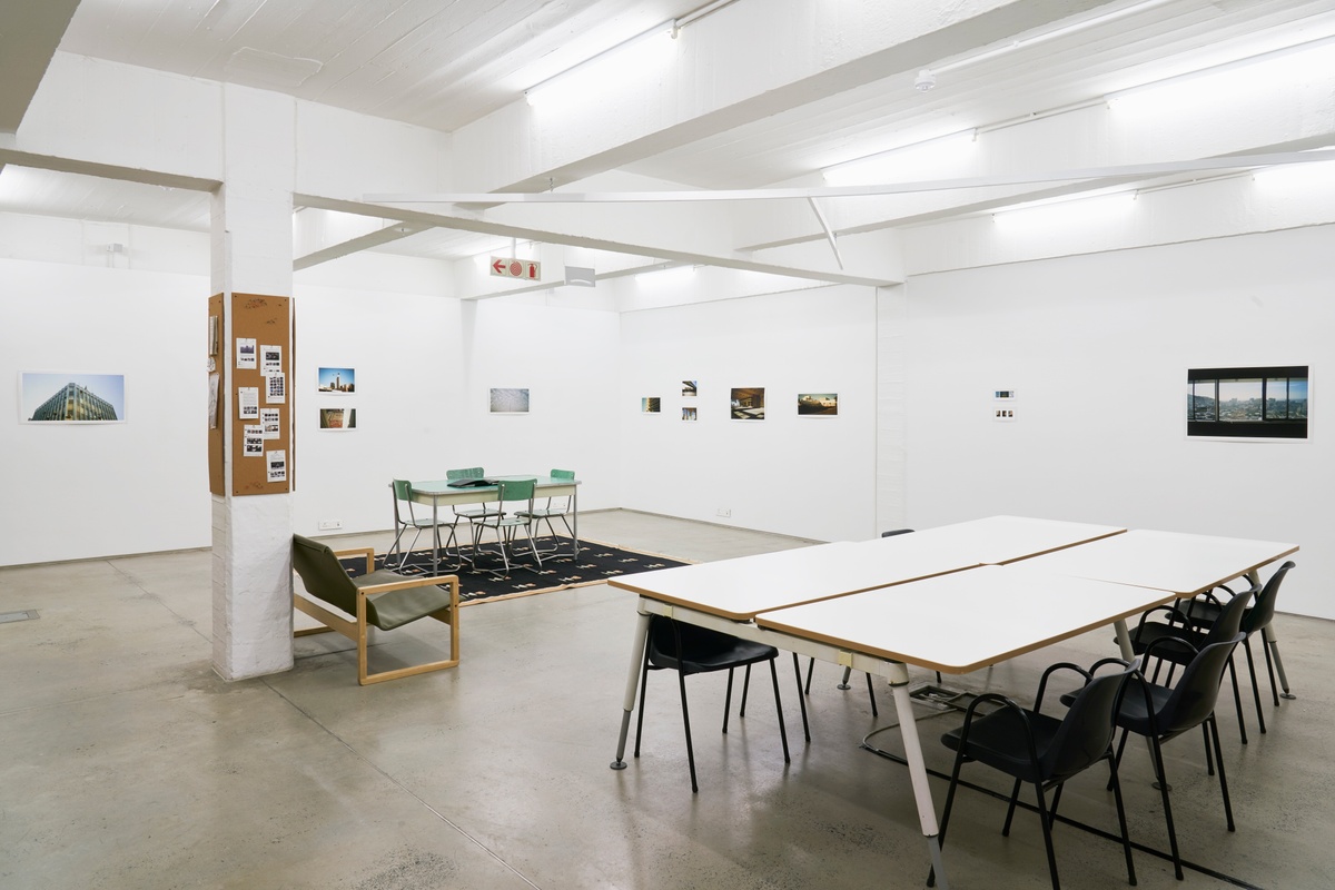 Installation photograph from the ‘Missing Subject’ exhibition in A4’s Library. In the middle, tables with seating. At the back, the walls are lined with Andile Phewa’s photographs.
