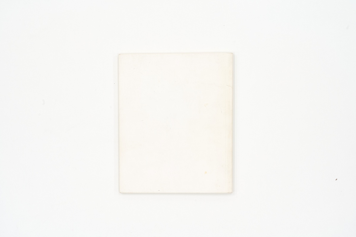 A topdown photograph of the back cover of Jane Alexander's photo-book 'PHOTO-BOOK: Photomontages by Jane Alexander' on a white background.
