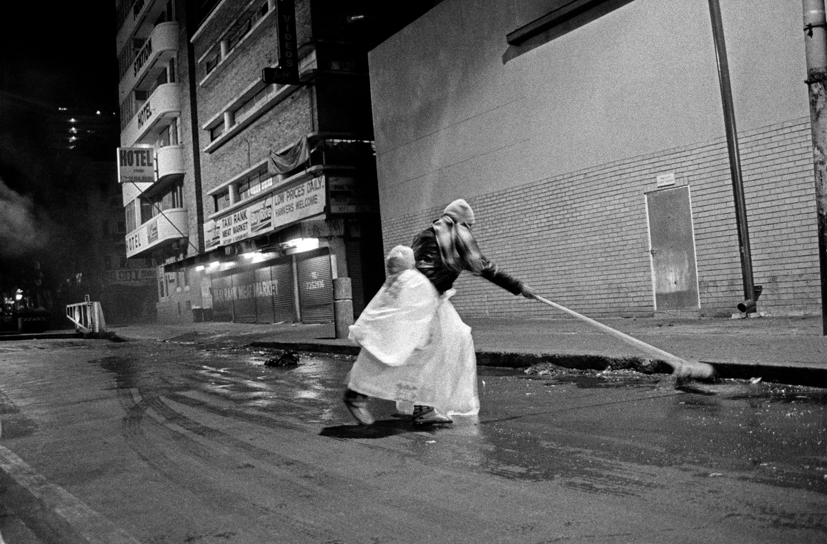 Artwork from Sabelo Mlangeni’s residency on A4’s top floor. The monochrome photograph ‘Low Prices Daily’ depicts a person sweeping water from a paved road with a broom.
