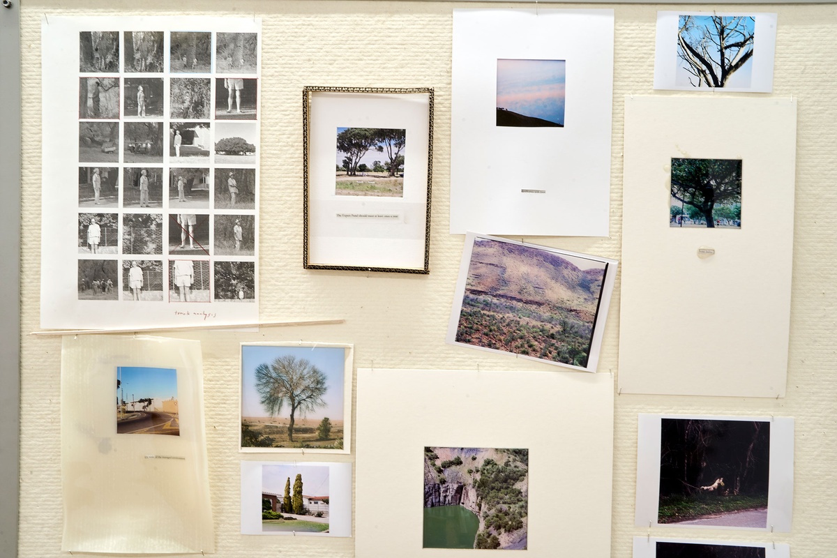 Installation photograph of Michael Tymbios’ studio during his residency in A4 Arts Foundation. A closeup view of a freestanding pinboard that features multiple text printouts and photographic prints.
