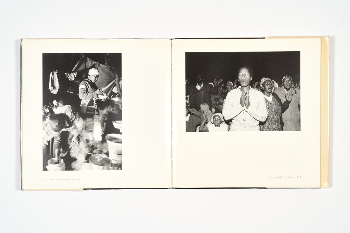 A topdown photograph of a 2-page spread from the photo-book 'South Africa: The Cordoned Heart' on a white background.
