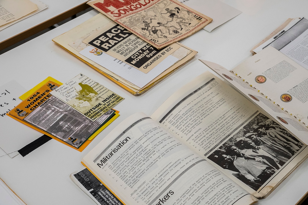Installation photograph from the ‘Gladiolus’ exhibition on A4’s ground floor that shows printed matter arranged on a table, with a booklet is open to the heading ‘Militarisation’.

