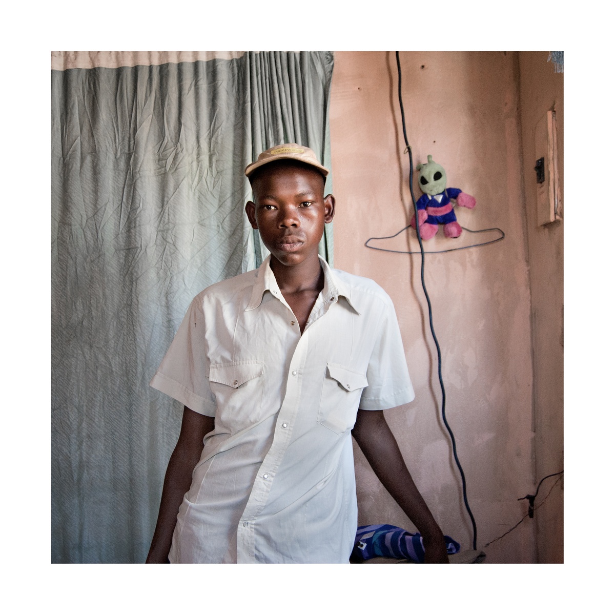 Photograph from Jabulani Dhlamini’s residency on A4’s top floor. At the back, a curtain covers a wall. At the front, a standing individual faces the camera.
