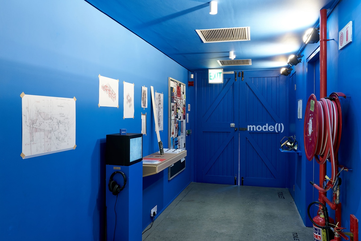 Installation photograph from the ‘mode(l)’ exhibition in A4’s Goods project space shows multiple works lining the walls.
