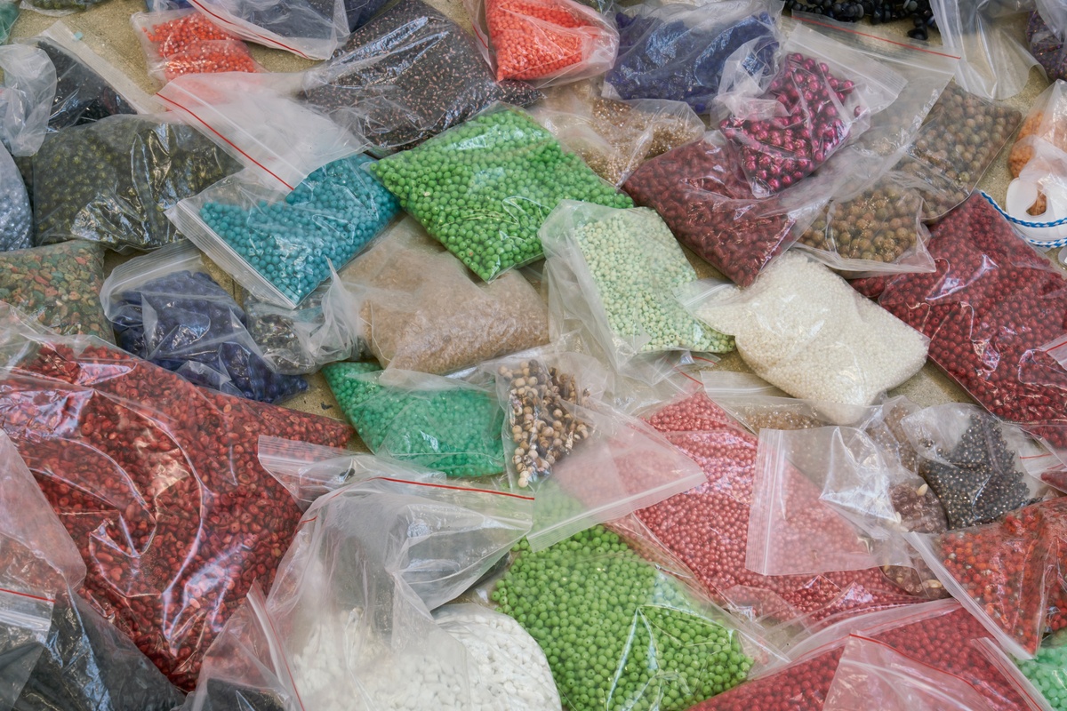 Process photograph from ‘Open Production’, Igshaan Adams’ hybrid studio/exhibition in A4’s Gallery. A closeup view of a table laden with variously coloured and sized beads in resealable plastic bags.
