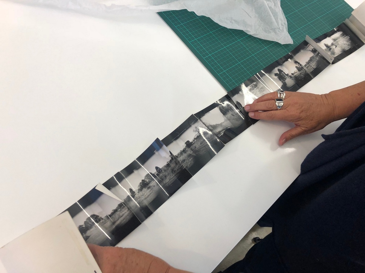 Process photograph from the offsite exhibition ‘Hay Tiempo, No Hey Tiempo’ at the Centro Fotográfico Álvarez Bravo, Mexico. An individual arranges a row of photographic prints on a white table.
