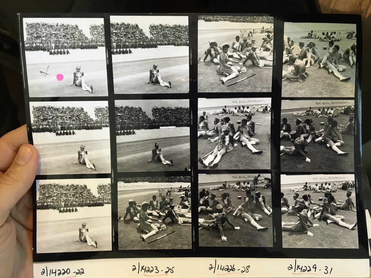 Process photograph from the making of Daniel Zimbler's documentary on David Goldblatt that shows a hand holding a photographic contact sheet.
