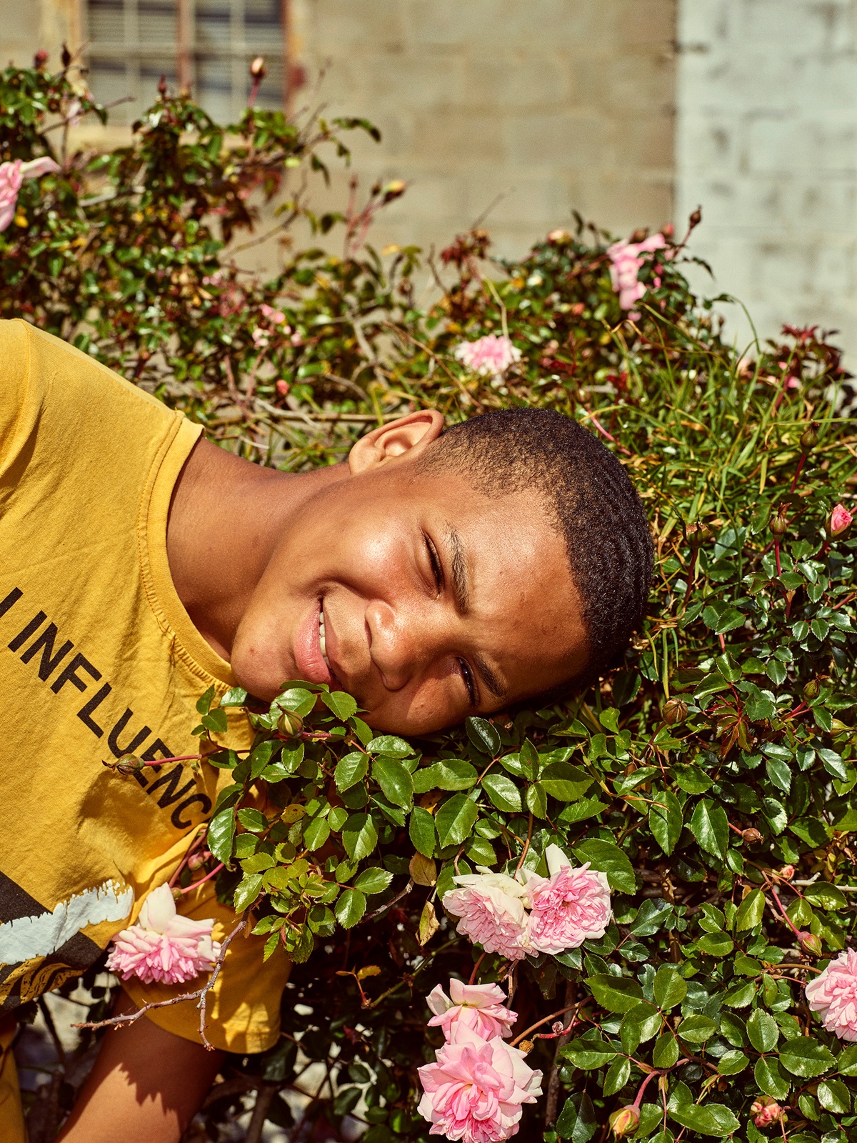 Photograph by Pieter Hugo, from A4’s ‘Atlantis Project’ exchange with the SWAGG United Dance Crew, that depicts a young person with their head rested on top of a flower bush.

