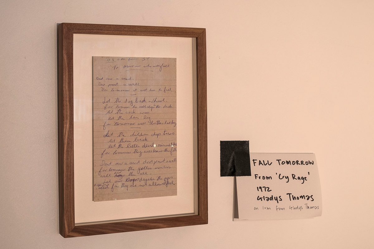 Installation photograph from the ‘Gladiolus’ exhibition on A4’s ground floor. A framed handwritten copy of Gladys Thomas’ poem ‘Fall Tomorrow’ is mounted on the wall.
