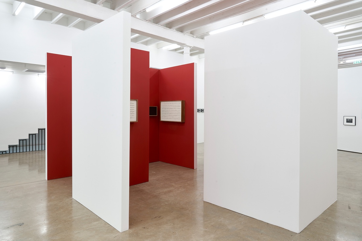 Installation photograph of the You to Me, Me to You exhibition. In the middle, four of Iñaki Bonillas’ sound and score installations from ‘The Return to the Origin’ series are mounted on freestanding walls painted white on the outside and red on the inside.
