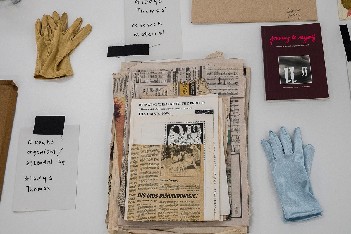 Installation photograph from the ‘Gladiolus’ exhibition on A4’s ground floor that shows printed matter arranged on a table. On the left, a stapled copy of Gladys Thomas’ ‘A walk along the promenade’. On the right, a photocopy of Thomas’ short story ‘Little boy lost in a township jungle’.
