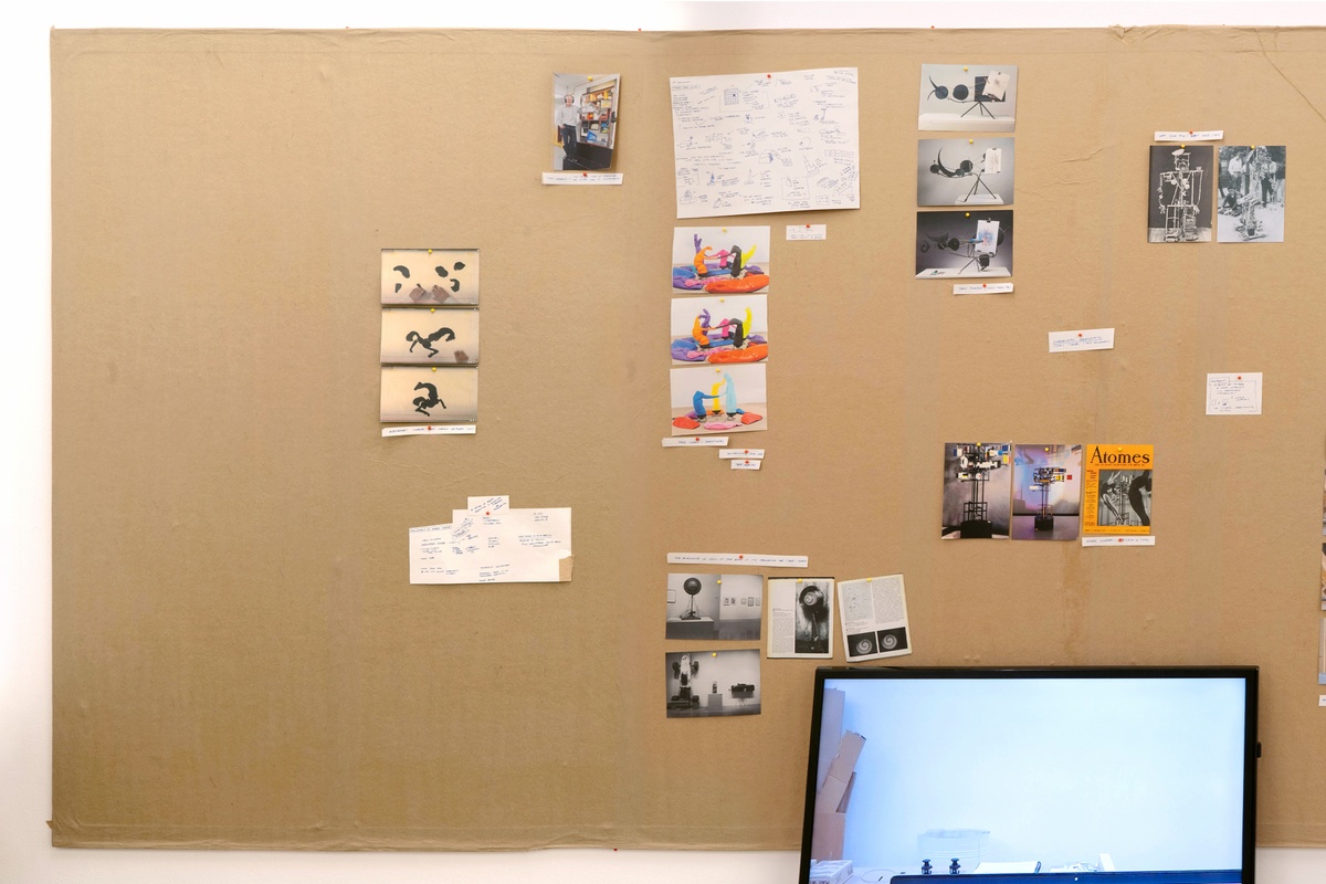 Installation photograph from Mitchell Gilbert Messina's residency in A4 Art Foundation. A wall-mounted strip of cardboard hosts pinned research notes.

