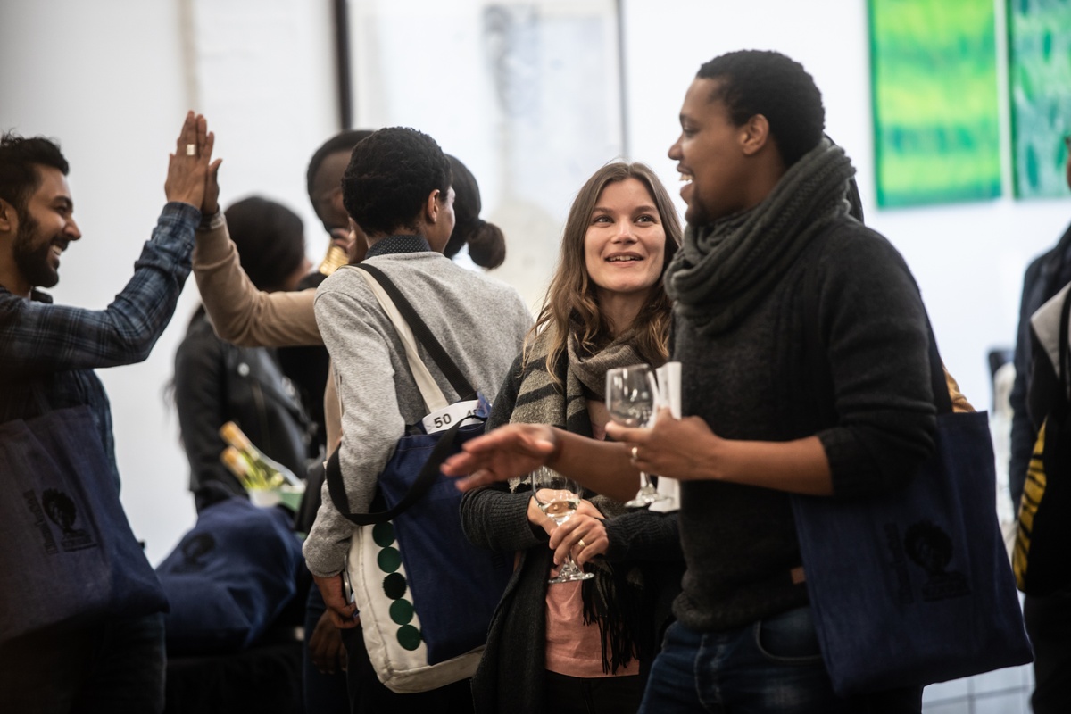 Event photograph from the opening of the “Ikhono LaseNatali” exhibition in A4’s Gallery that shows attendees with wine glasses in A4’s foyer.
