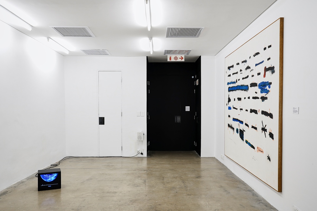 Installation photograph from the ‘Sounding the Void, Imaging the Orchestra V.1’ exhibition in A4’s Gallery. On the right, Jared Ginsburg’s mixed media painting ‘Backdrop no. 2 (backdrop as sculpture)’ is mounted on the gallery wall. On the left, Chris Chafe’s video 'The 1200-year Climate Podcast (an excerpt)’ playing on a square screen on the floor.
