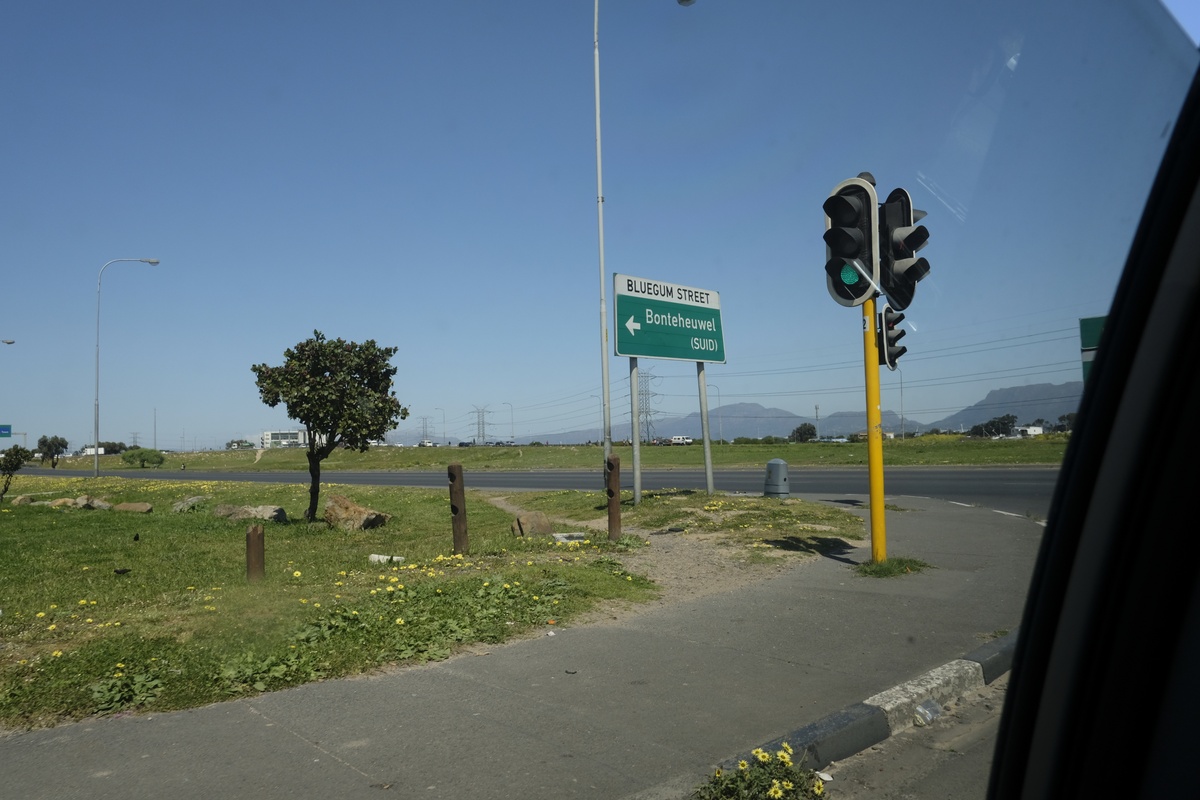 Process photograph from a visit to the Bonteheuwel township that formed part of ‘Open Production’, Igshaan Adams’ hybrid studio/exhibition in A4’s Gallery. A green and white corner road-sign that reads ‘Bluegum Street, Bonteheuwel (SUID)’  sits next to a traffic light.

