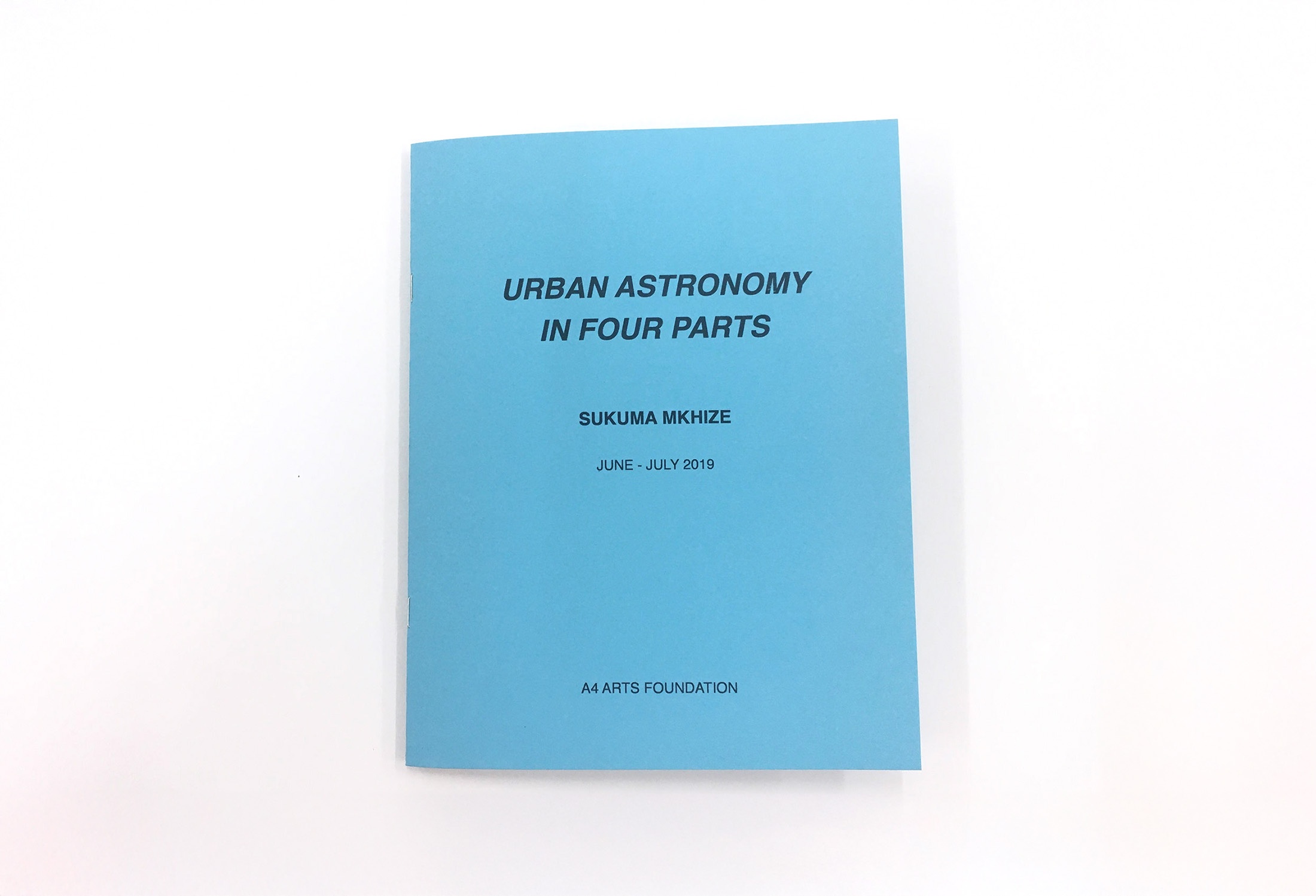 Photograph of ‘Urban Astronomy in Four Parts,’ a zine by Sukuma Mkhize from his residency at A4. The blue cover reads ‘Urban Astronomy in Four Parts, Sukuma Mkhize, June - July 2019, A4 ARTS FOUNDATION.’
