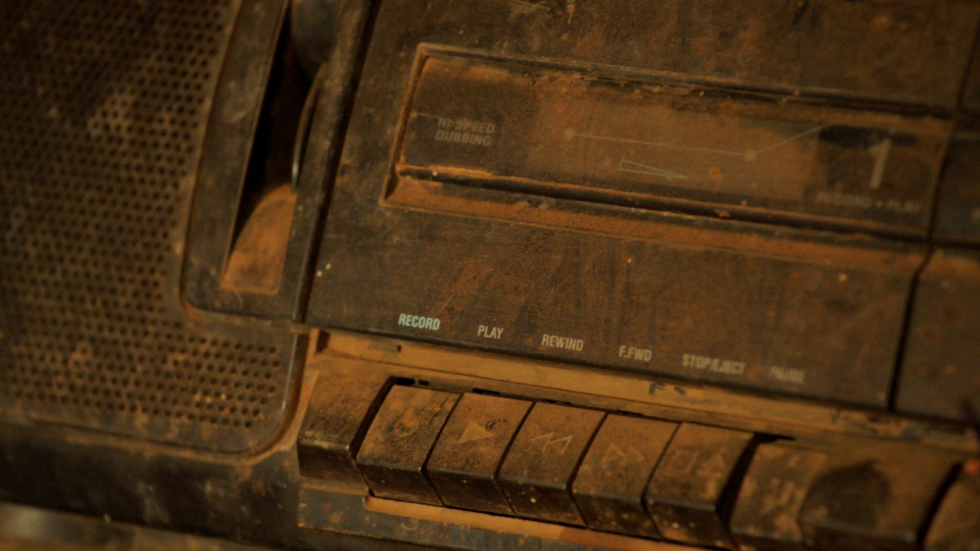 Still frame from ‘A Story of Sahel Sounds’ documentary by the neopan kollectiv, screened in A4’s Gallery as part of the 'Sounding the Void, Imaging the Orchestra V.1’ exhibition. It depicts a closeup detail of a dust covered cassette player.
