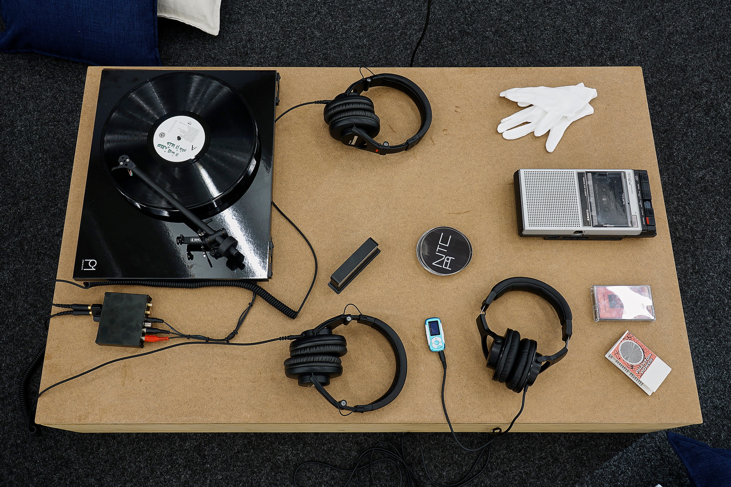 Installation photograph from the ‘Sounding the Void, Imaging the Orchestra V.1’ exhibition in A4’s Gallery. A closeup view of a listening station with a record player, headphones and cassette player.
