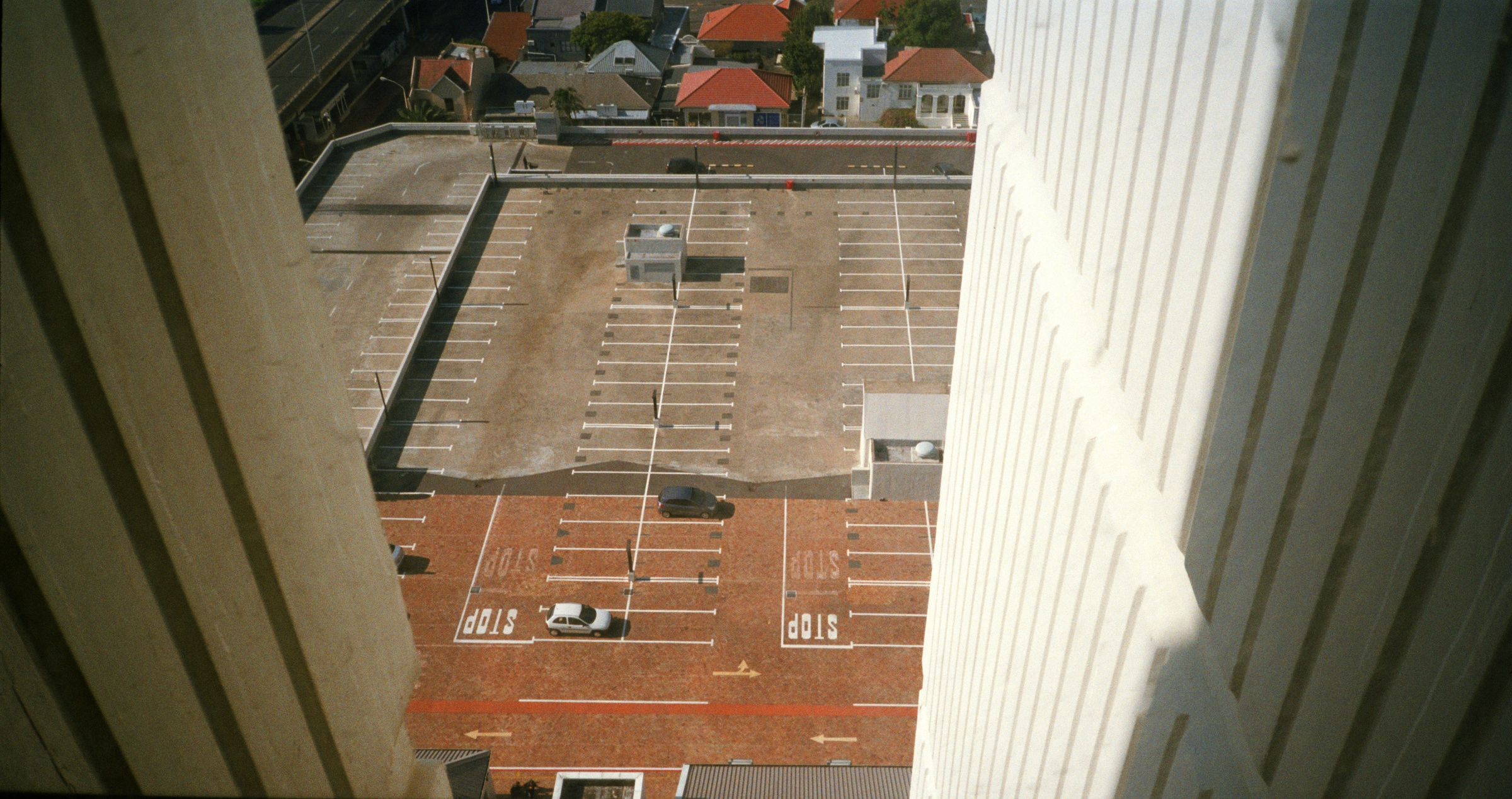 Artwork image from the ‘Missing Subject’ exhibition in A4’s Library. Andile Phewa’s photograph ‘Spy’ depicts a rooftop parking lot from a higher vantage point.
