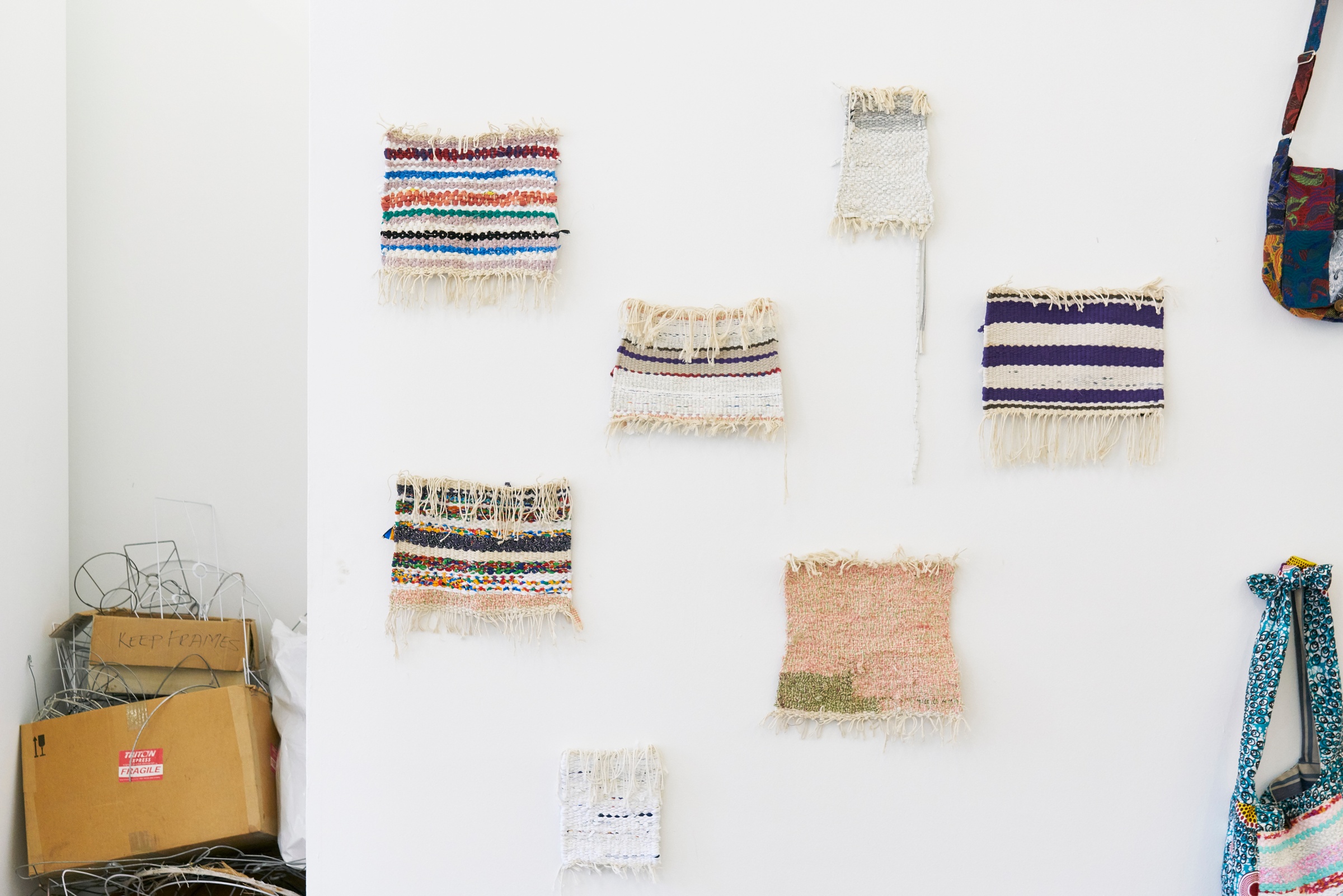 Event photograph from the Scalabrini Workshop that formed part of ‘Open Production’, Igshaan Adams’ hybrid studio/exhibition in A4’s Gallery. Swatches of woven fabric bordered with loose threads arranged on a white wall.
