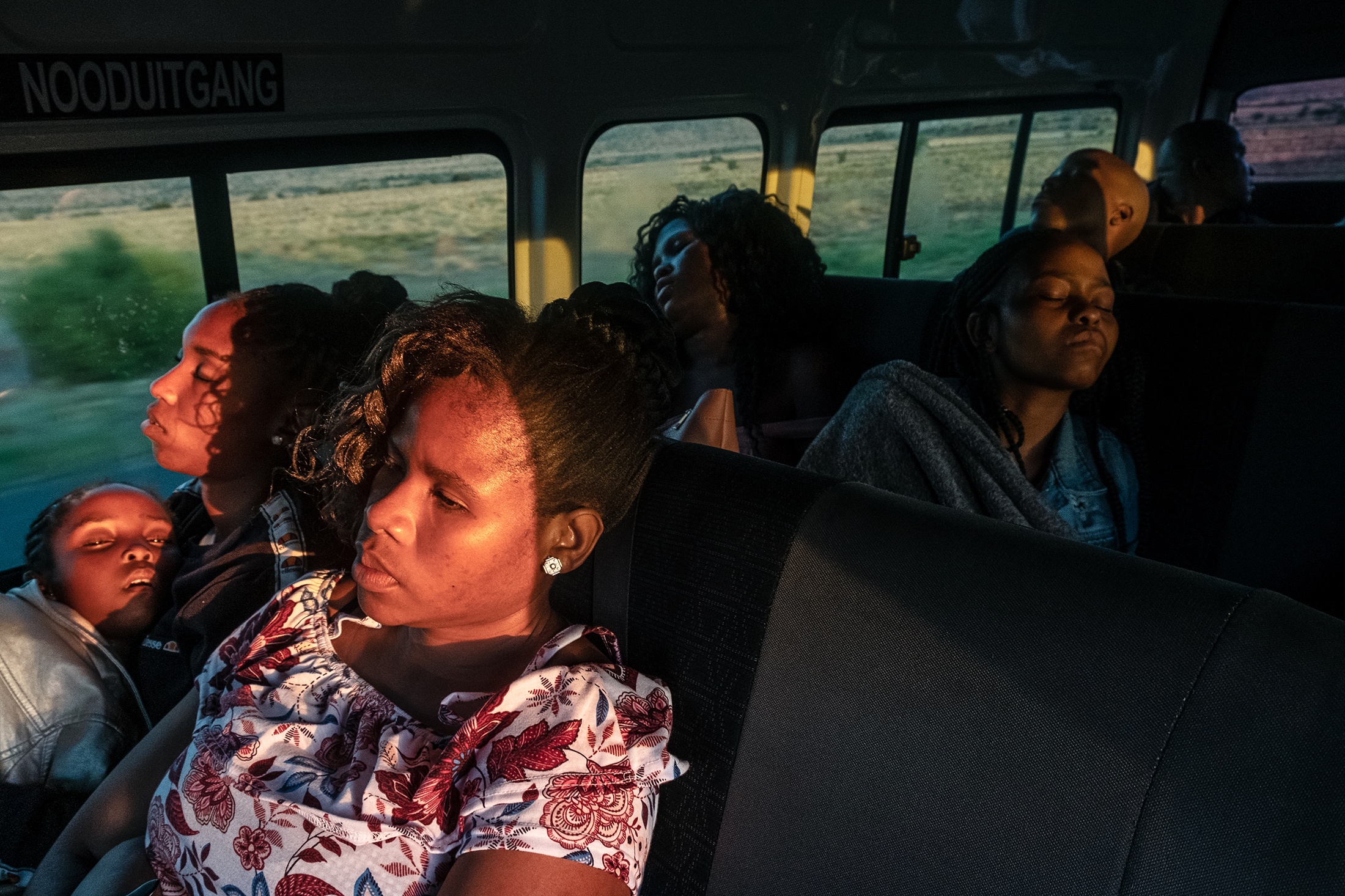 Lindokuhle Sobekwa's photograph 'Ziyaphuma ezicweleyo' shows individuals seated in a bus, several of them seemingly asleep.

