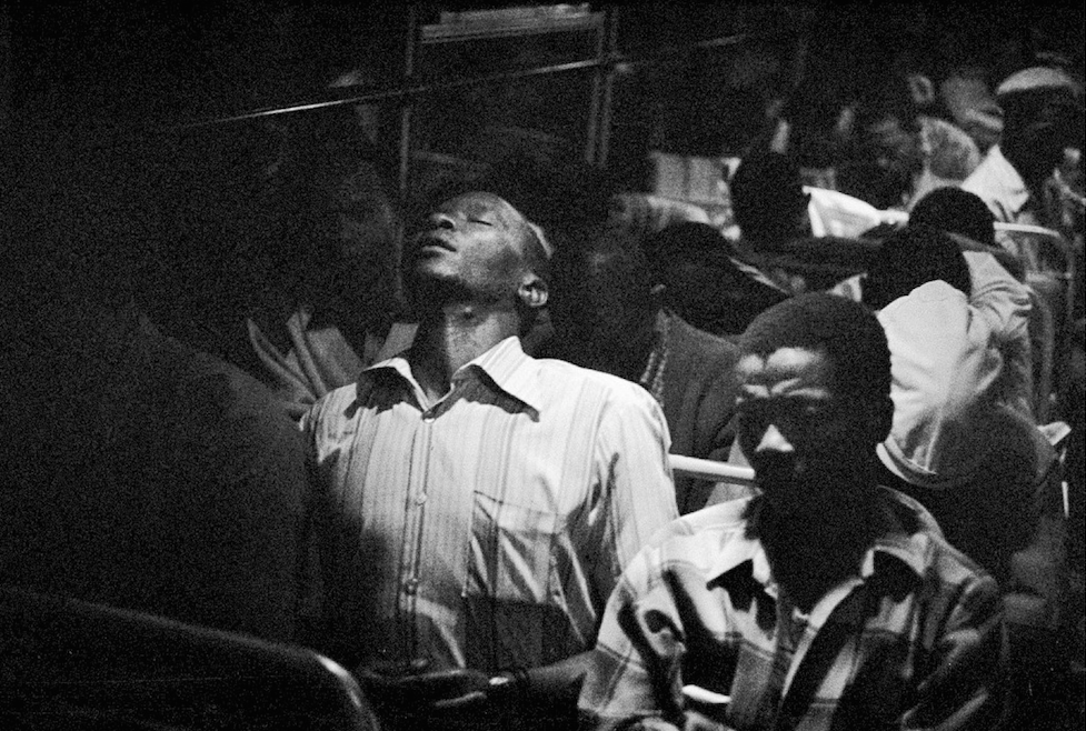 David Goldblatt's monochrome photographic print 'Going home: Marabastad-Waterval bus: 8.45pm, 45 minutes to the terminal' show individuals seated in a bus, several of them asleep.
