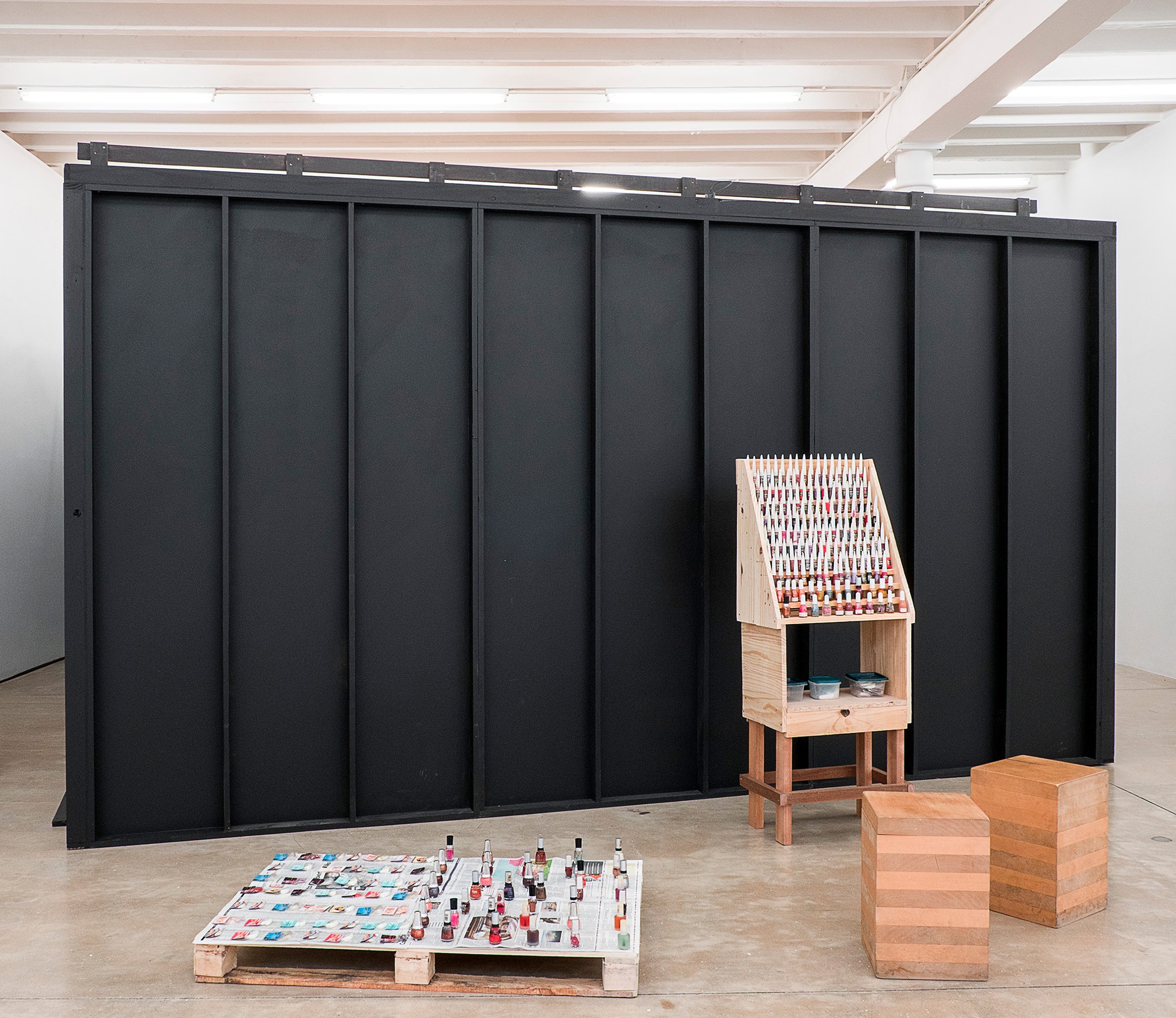 Installation photograph from the You & I exhibition in A4’s Gallery. On the left, Avant Car Guard’s granite and enamel sculpture 'Bury J.H.P. "Kendel" Geers' sits on the gallery floor. In the middle, Meschac Gaba’s sculptural installation ‘Vernissage’ sits on the gallery floor.
