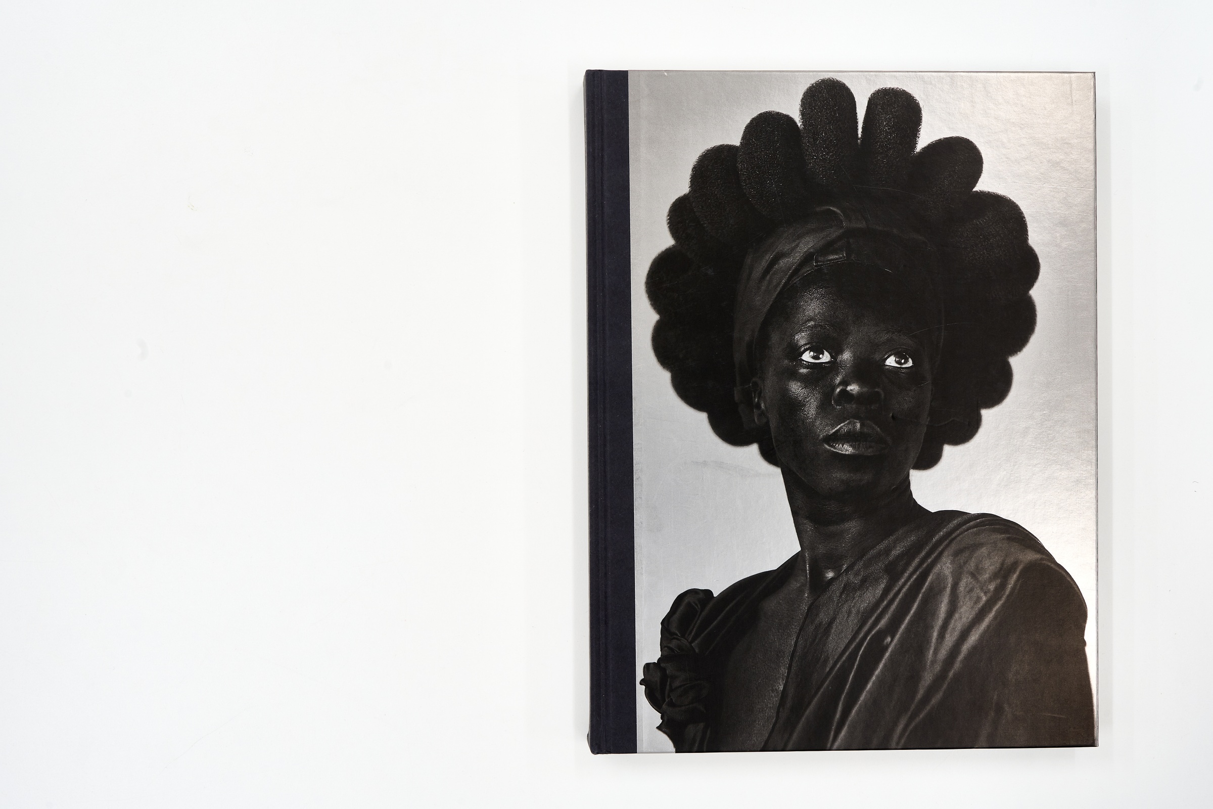 A topdown photograph of the cover of Zanele Muholi's photo-book 'Somnyama Ngonyama: Hail the Dark Lioness' on a white background.
