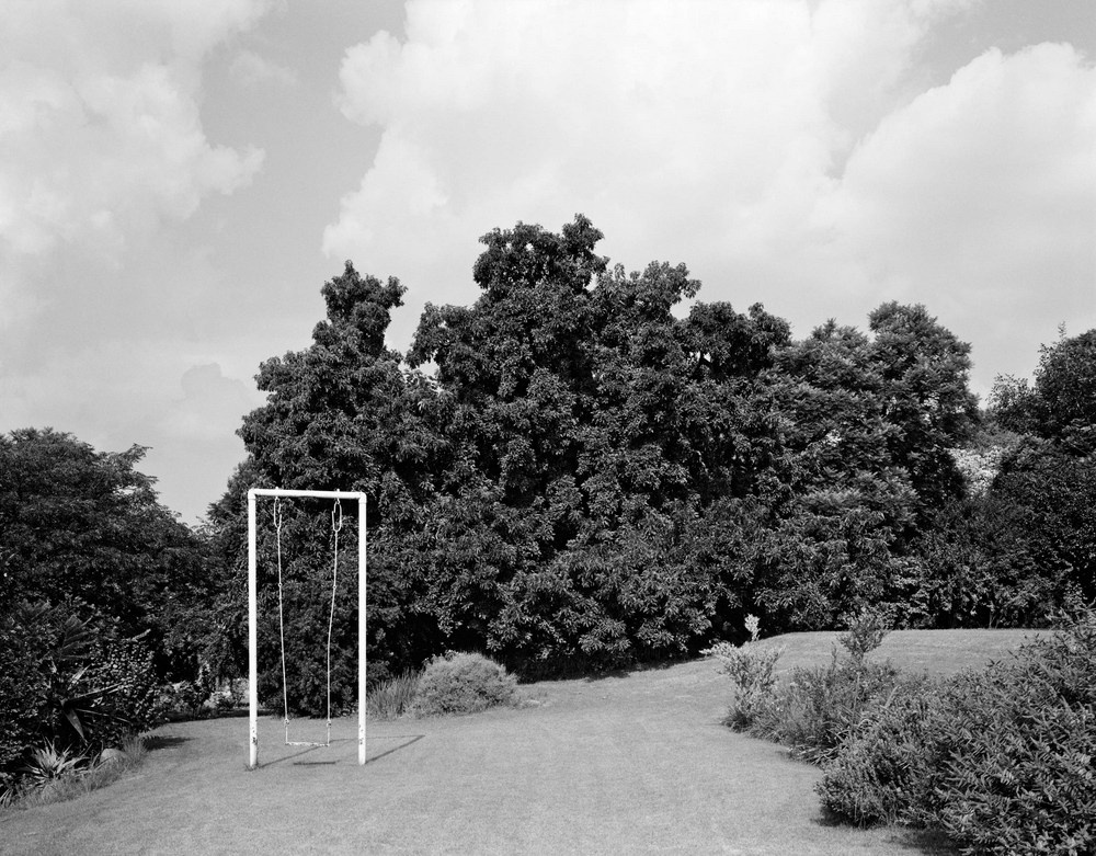 David Goldblatt's black-and-white photograph 'In the garden of Felicia and Sydney Kentridge, Houghton, Johannesburg' shows a well-tended garden with a swing to the left.
