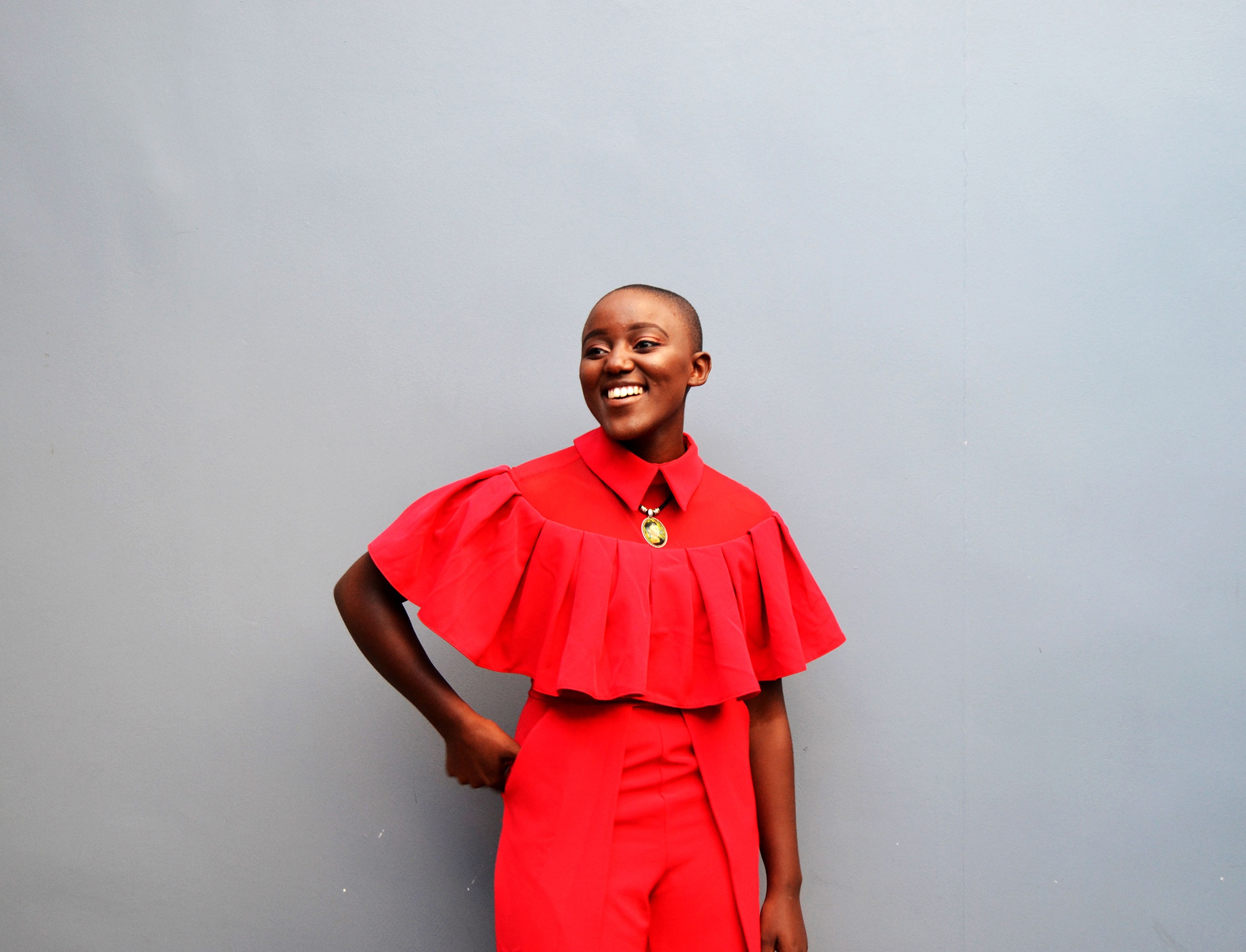 Event photograph from book launch of ‘The Truth Shall Bloom’ by Tabogo Nong on A4’s top floor, that shows Nong posing in front of a grey wall.
